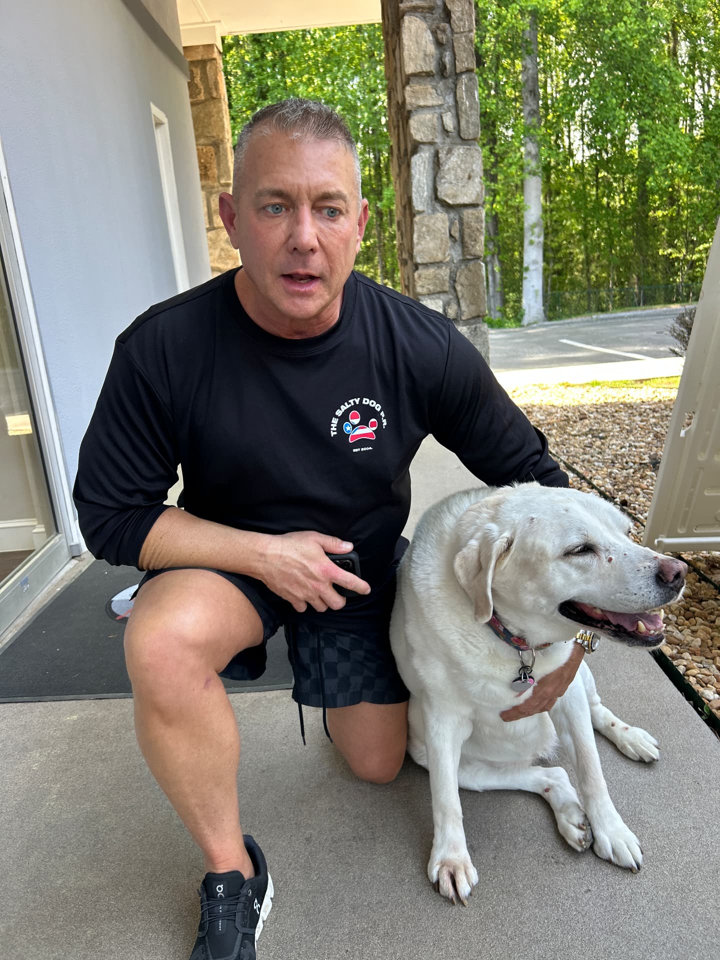 Client kneeling with his white Labrador retriever outside the clinic